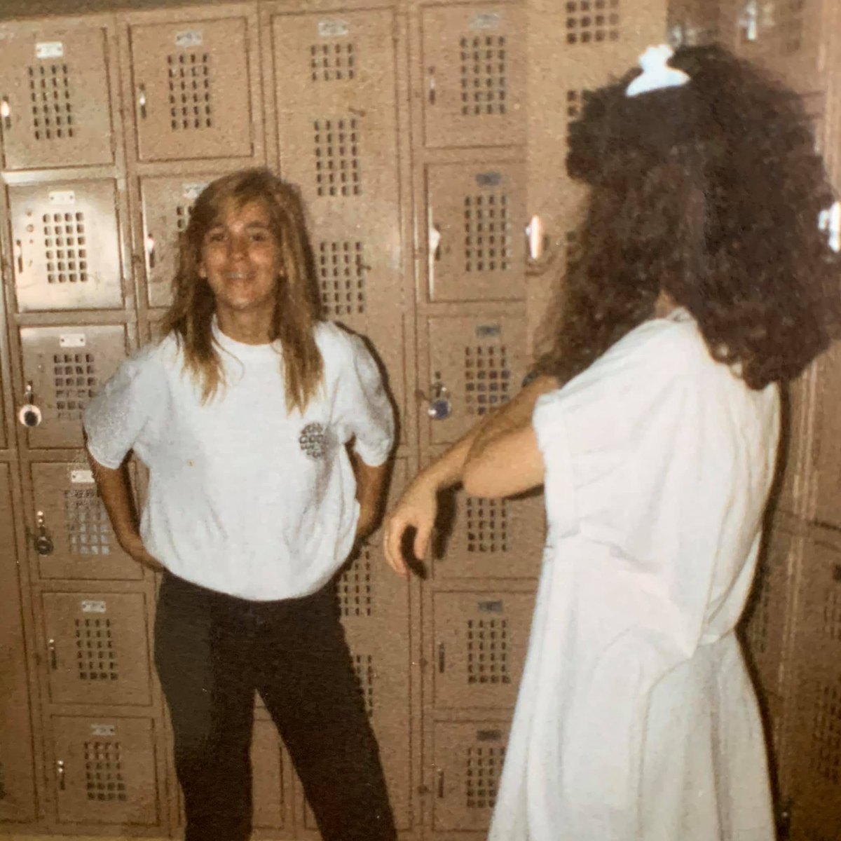 Two students talking in front of a wall of school hallway lockers